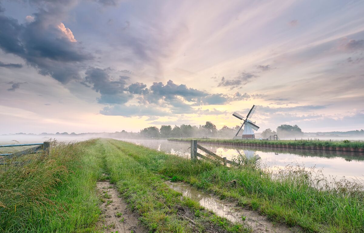 beautiful morning over charming windmill by river 